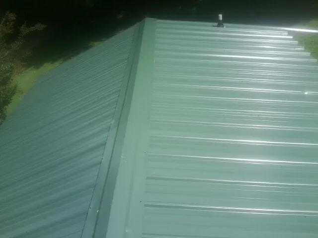 New green metal panels meeting at the ridge of a roof — Flat Roof Repair work by our crew in Wendover