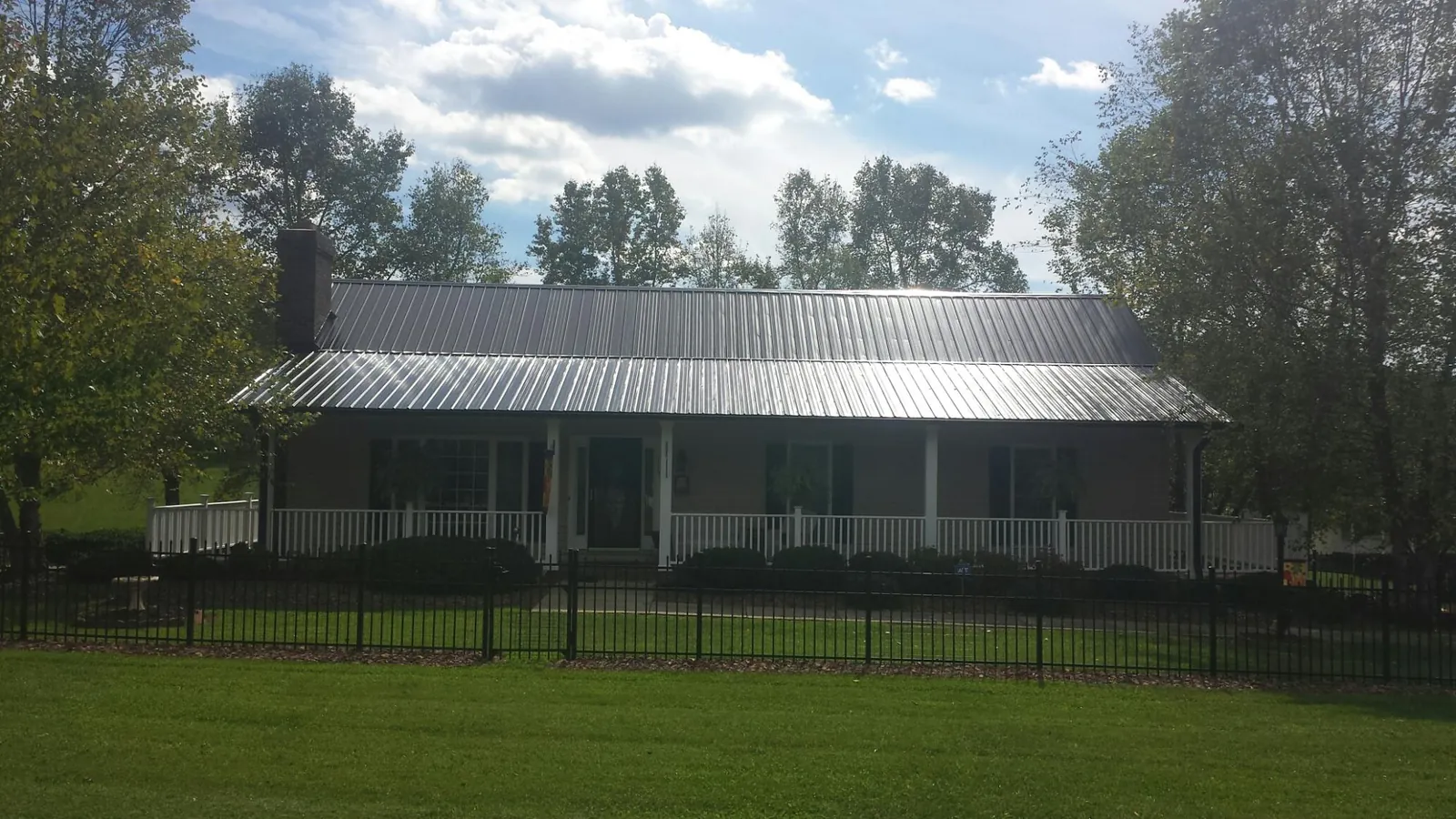 Gray metal roof on a brick ranch with a full width front porch — Gutter Guard Installation work by our crew in Wendover