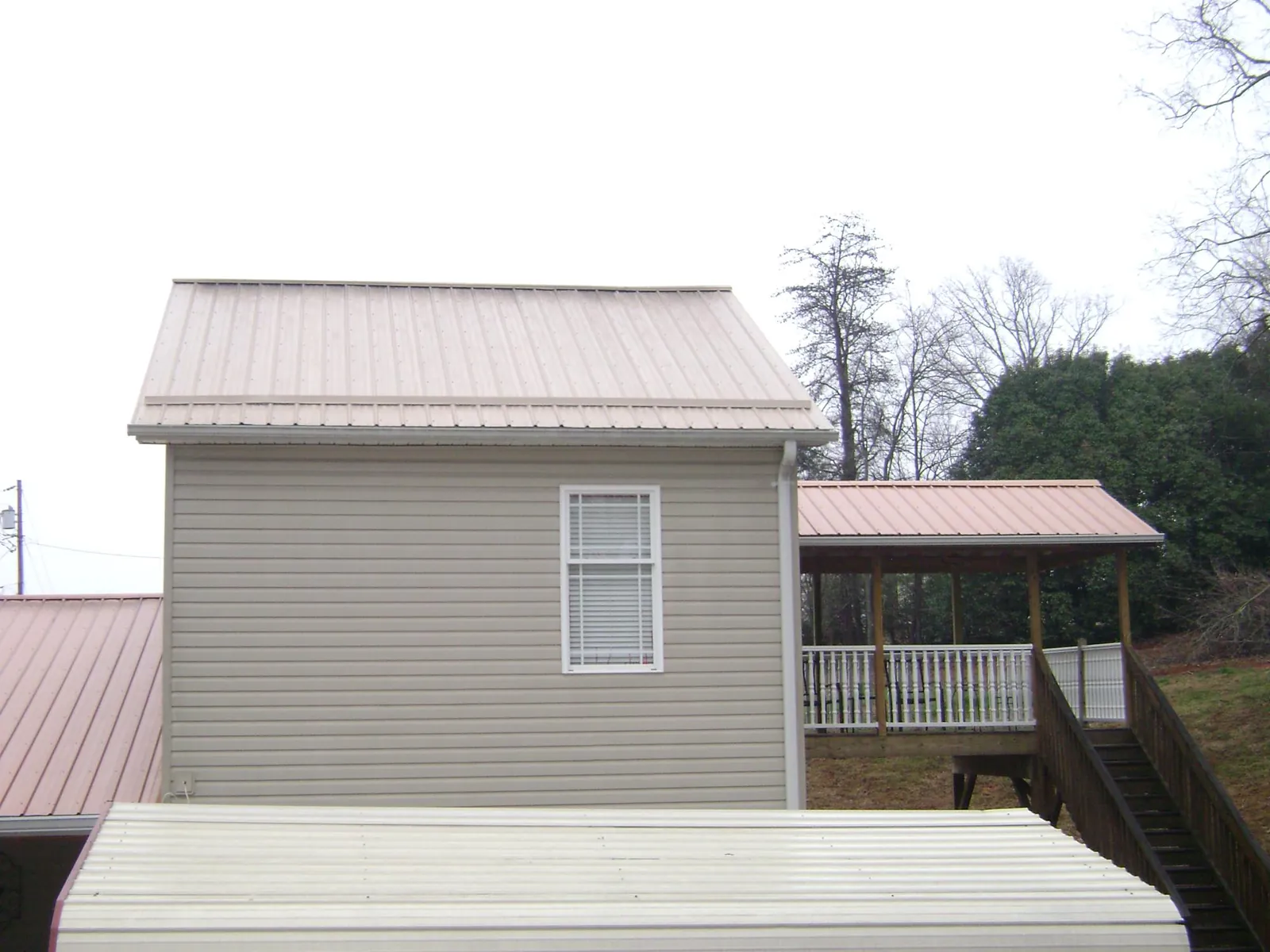 Tan metal roofs on a two story addition and attached porch, from a Roof Replacement job in Wendover