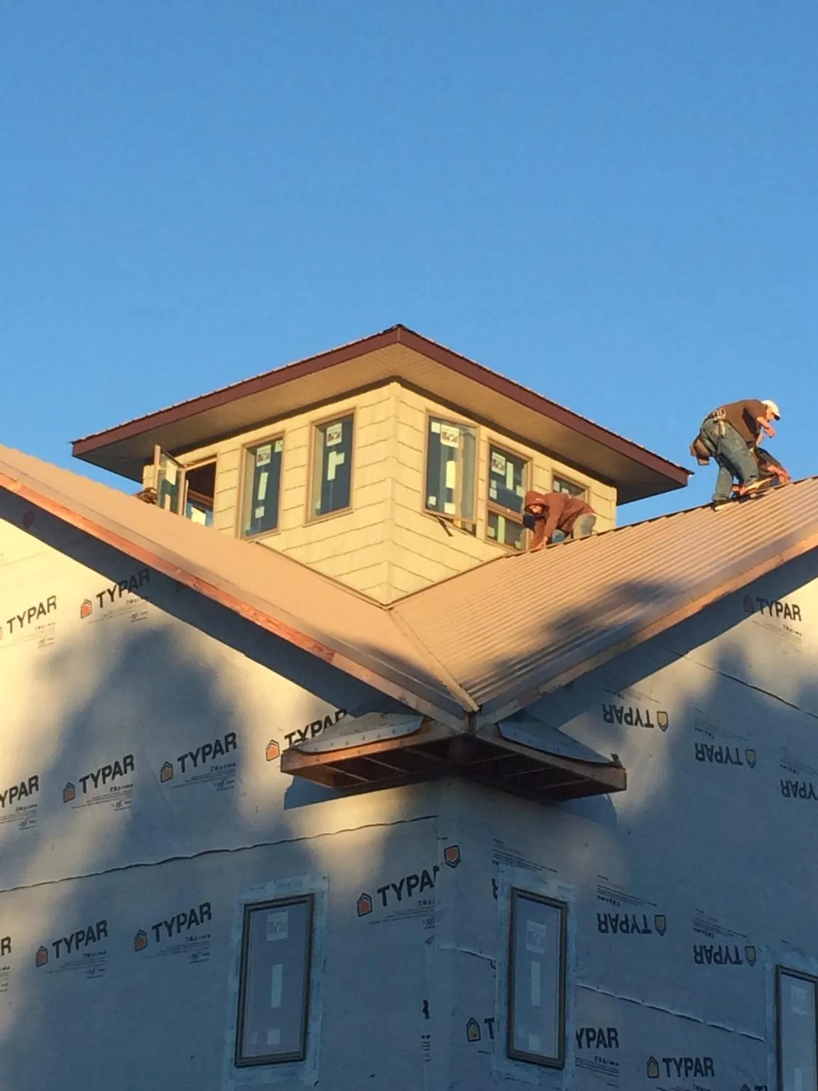 Roofers working around a rooftop cupola on a new metal roof at sunset — Roof Waterproofing in Wendover by Roofing Brothers
